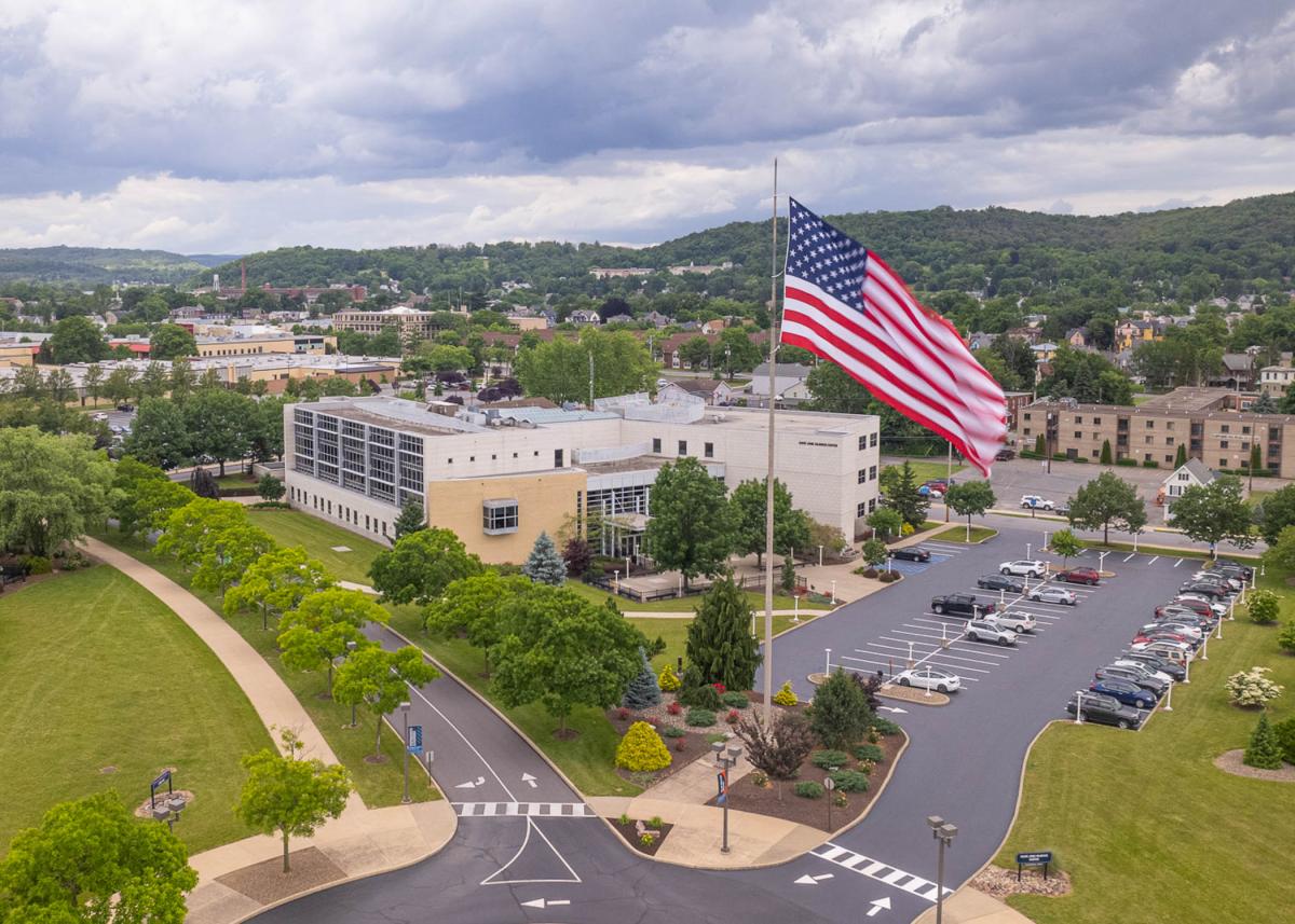 Aerial view of Pennsylvania College of Technology main campus with large U.S. flag hanging in foreground.
