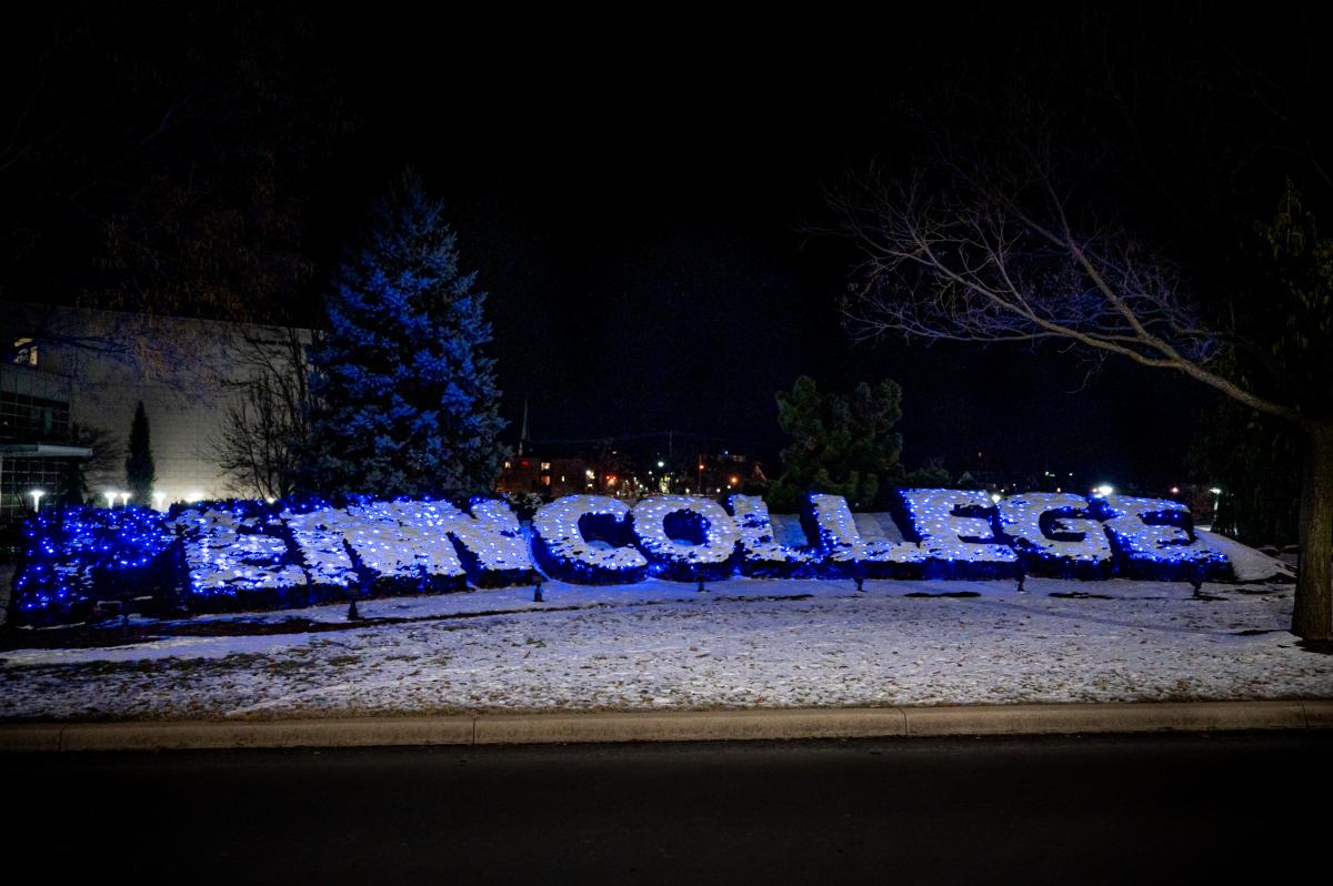 Shrubbery near Penn College's main entrance, which is sculpted to spell "Penn College" is covered in blue lights and a coating of snow.