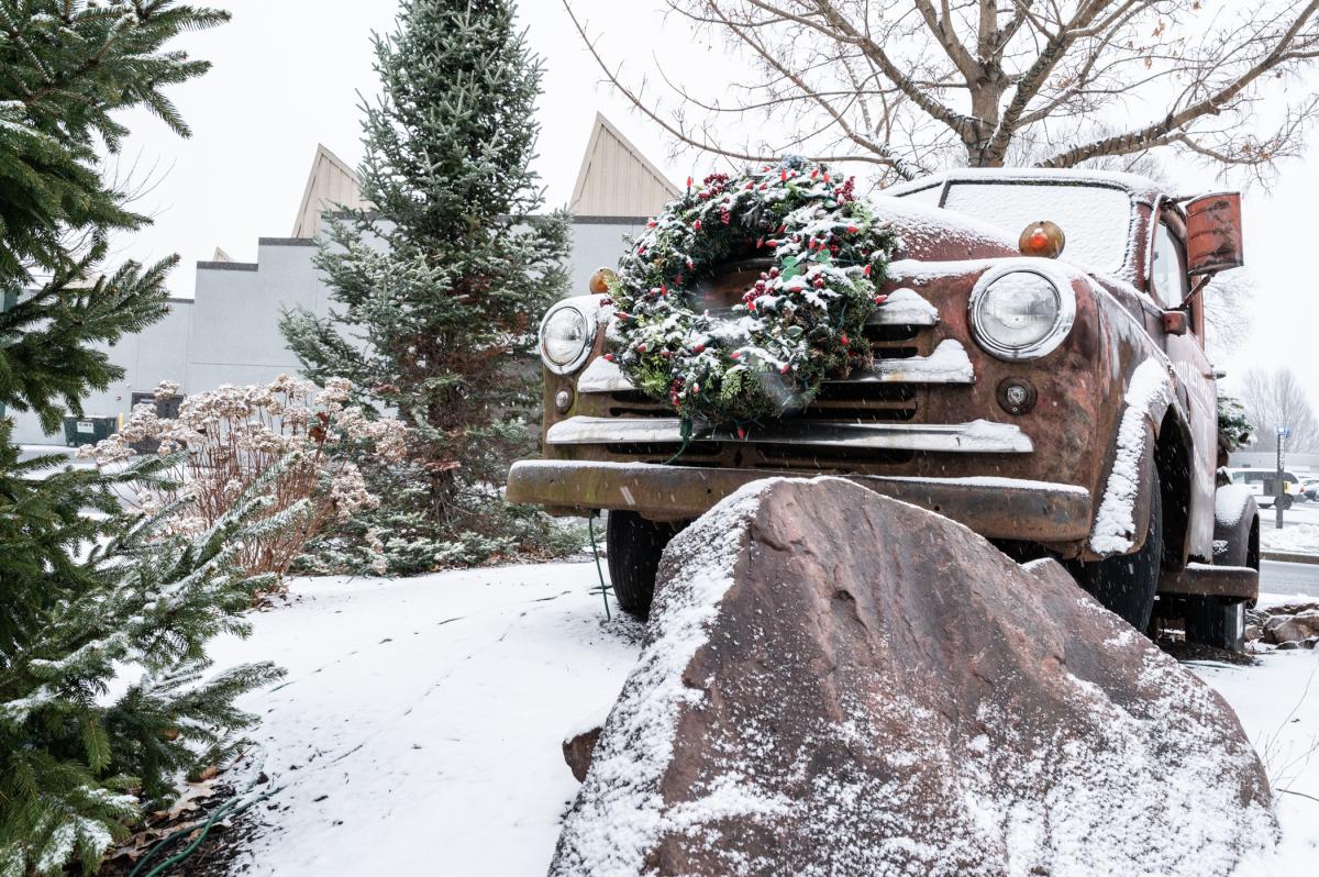 An antique pickup truck converted into a water feature is decorated with a wreath and coated in snow.