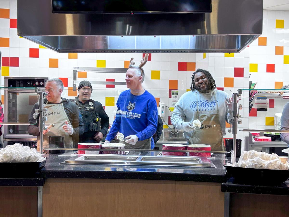 Food service counter with several people wearing aprons and gloves, serving ice cream.