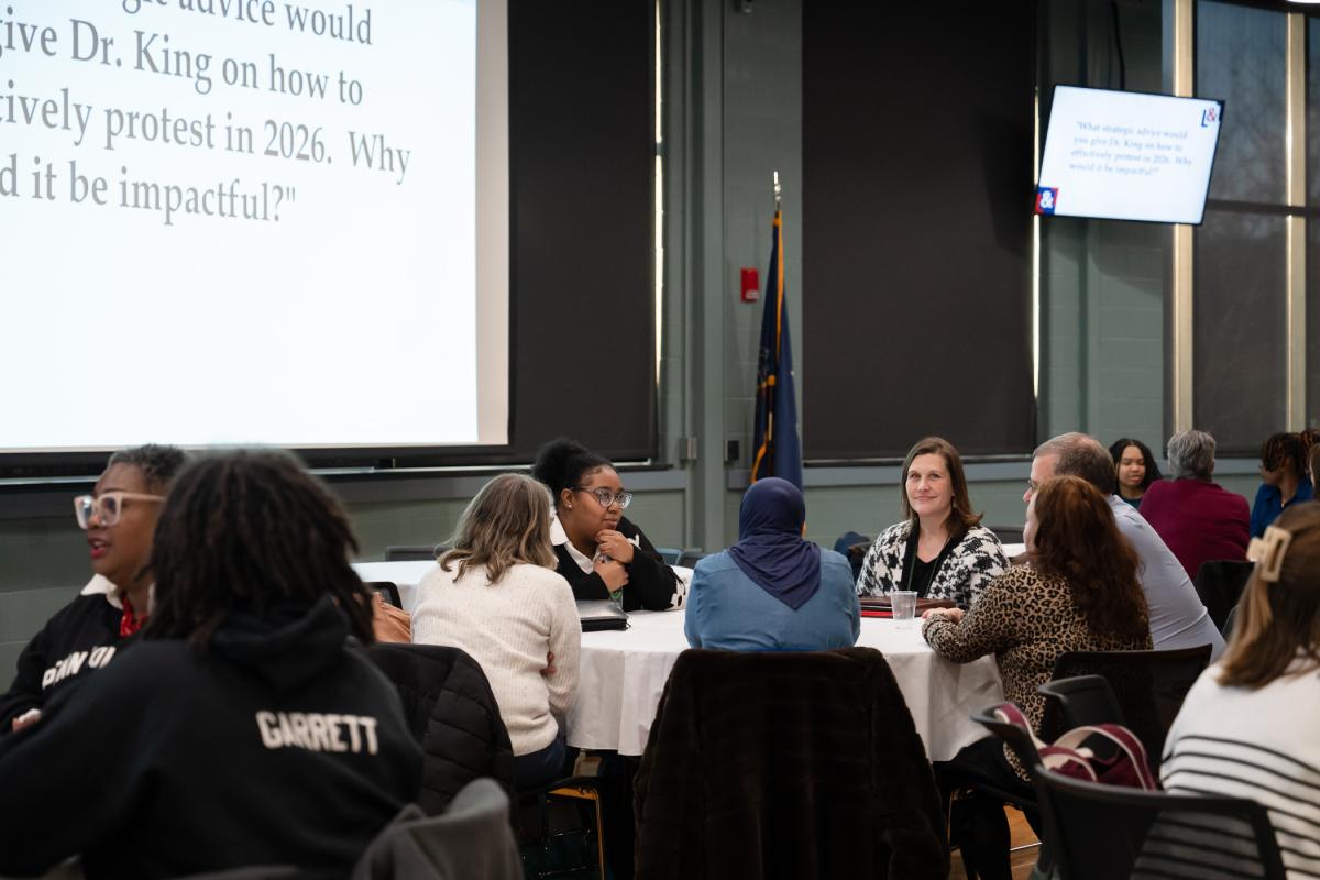 People converse while seated around round tables.