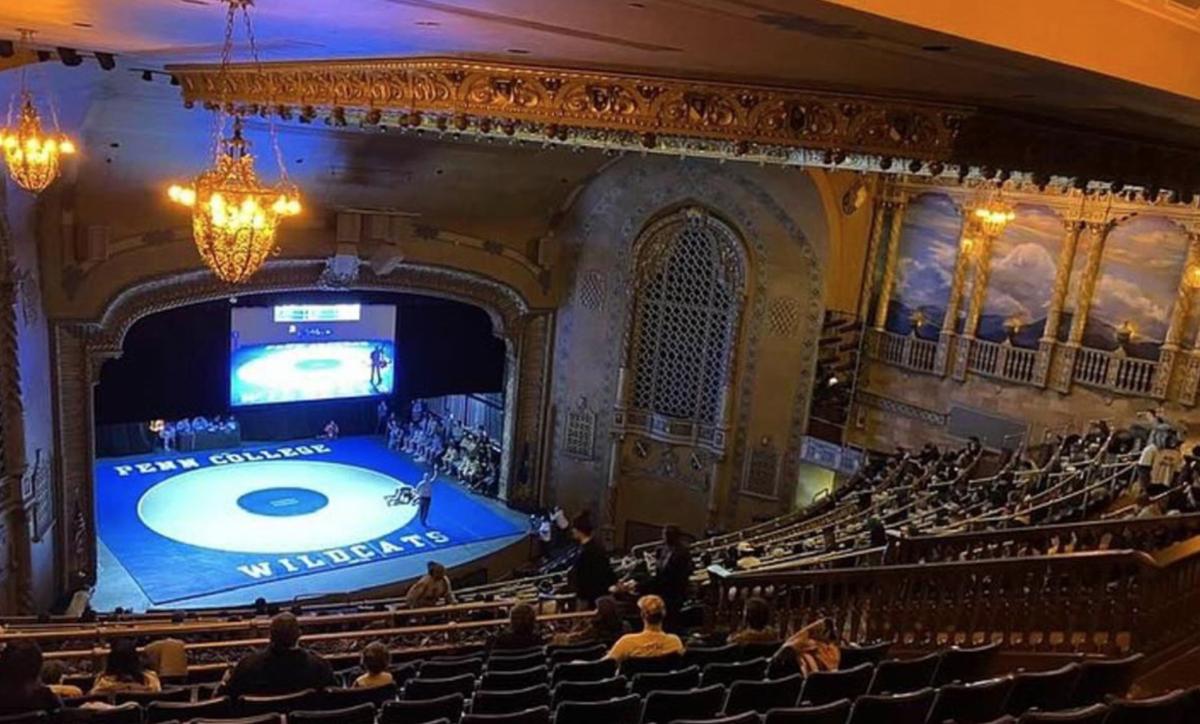 Collegiate wrestlers wrestle on a Penn College wrestling mat on the stage at the Journey Bank Community Arts Center.