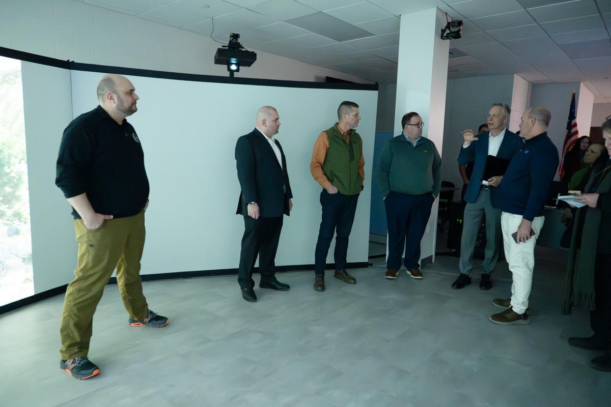 People chat near large video screens.