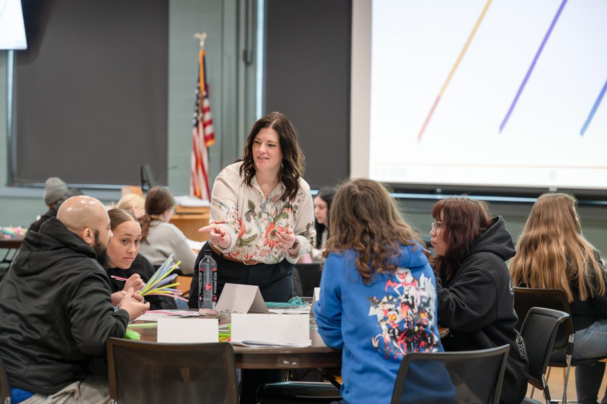 A woman interacts with students who are seated at a round table Penn's Inn at Penn College.