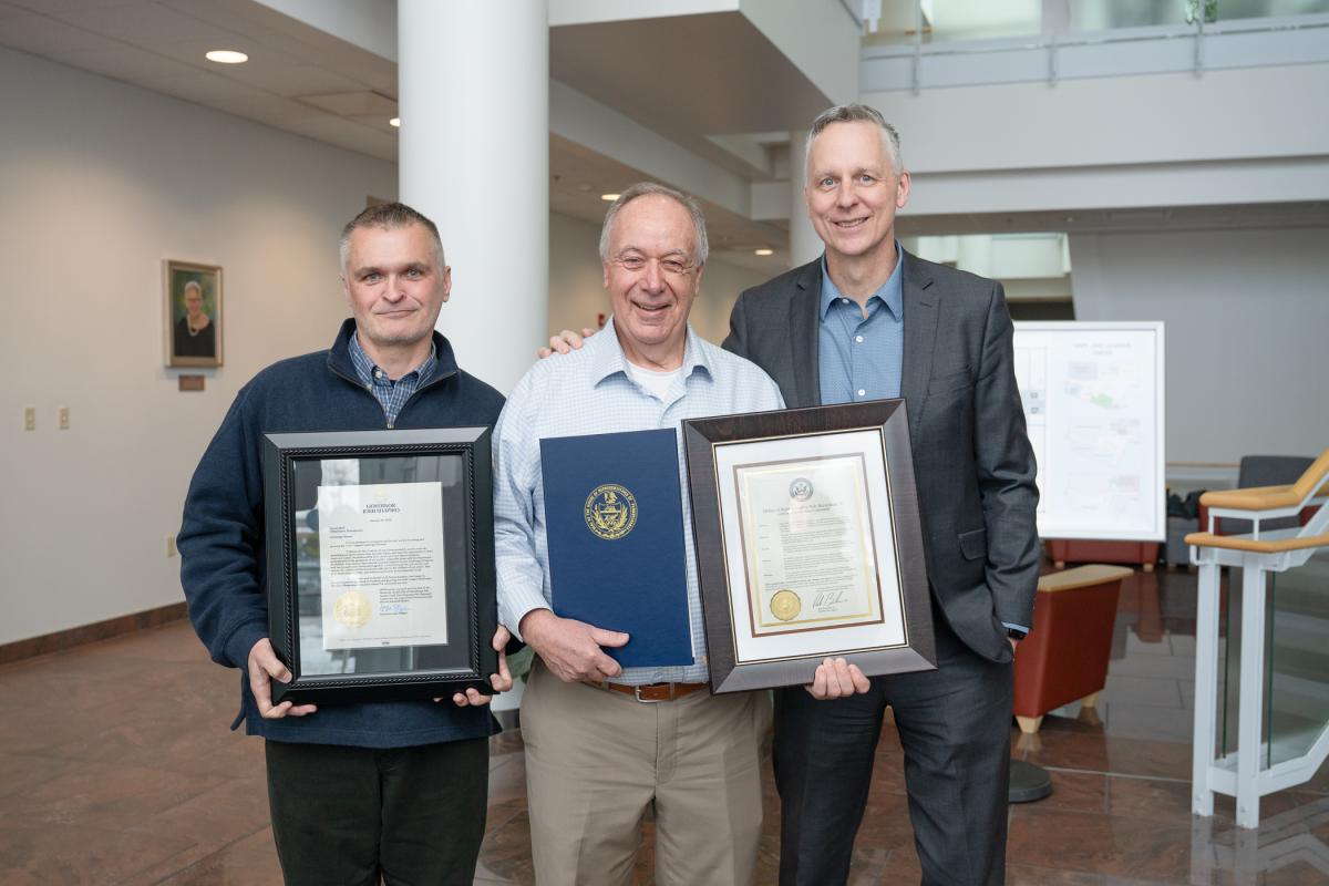 Three men stand side-by-side, holding certificates.