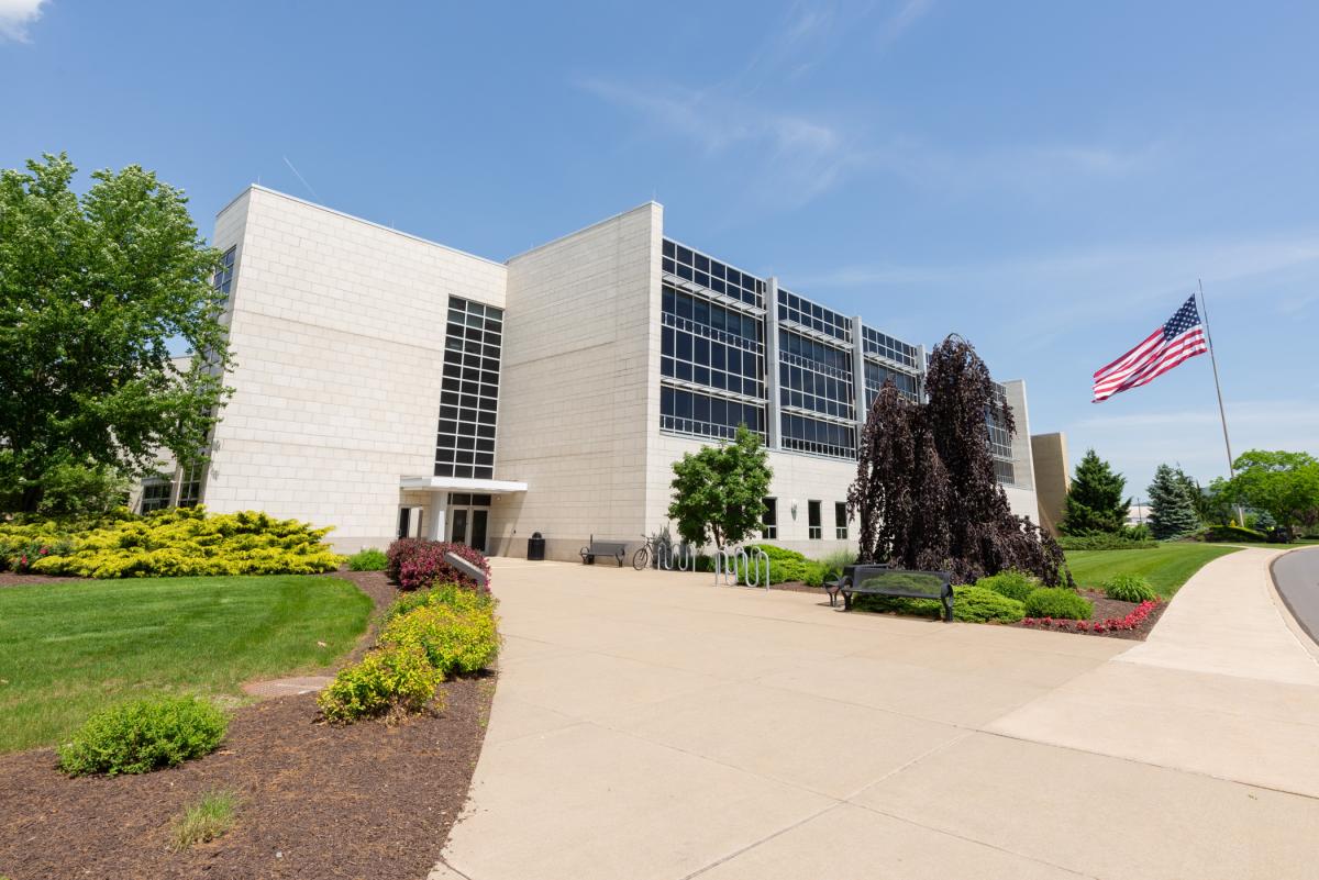 Davie Jane GIlmour Center north side with U.S. flag flying in the background against a clear sky.
