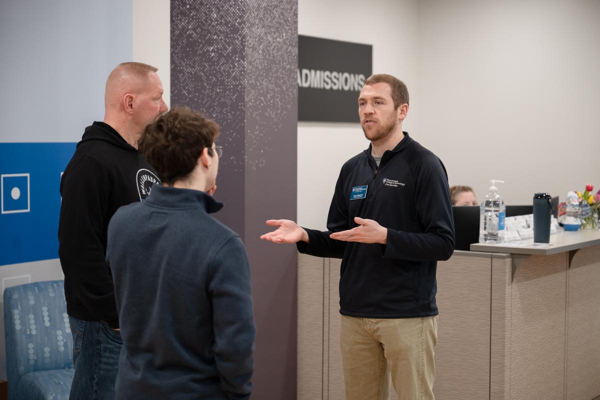 An Admissions Counselor speaks with a student and parent in the Admissions lobby.
