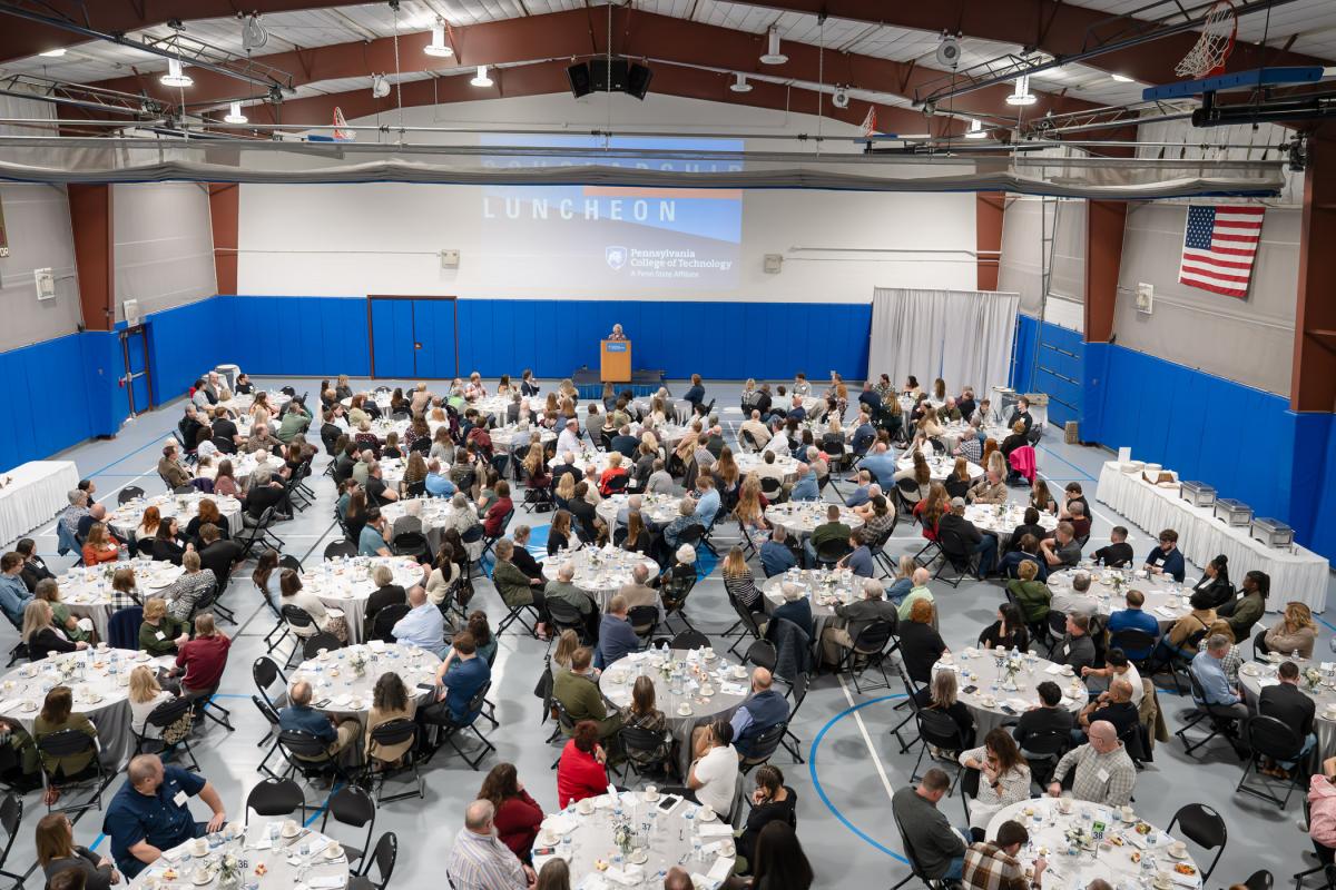 Overhead shot of the Penn College Field House during the Scholarship Luncheon, showing more than 40 round tables filled with people in business attire.