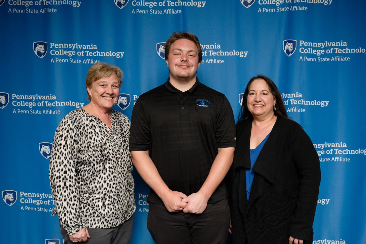 Three people stand in front of a Penn College "step-and-repeat" backdrop.