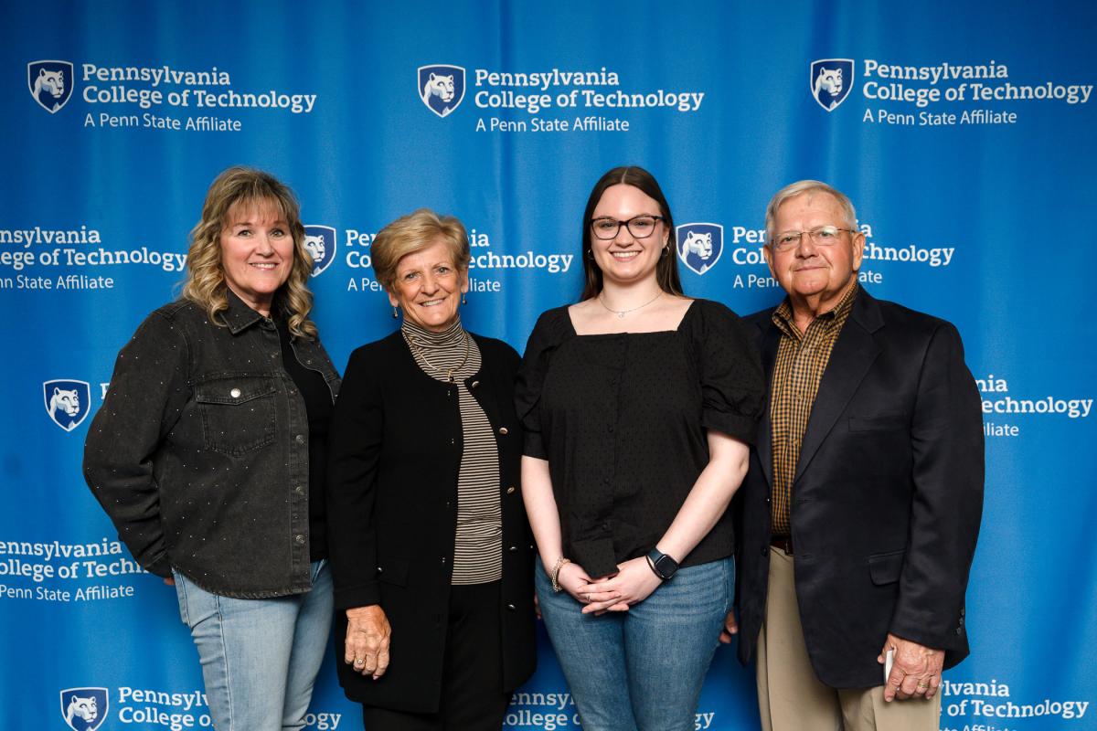 Four people stand in front of a Penn College "step-and-repeat" backdrop.