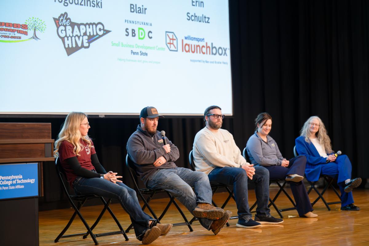 Five people sit on the stage of Penn College’s Klump Academic Center Auditorium. One is speaking into a microphone.