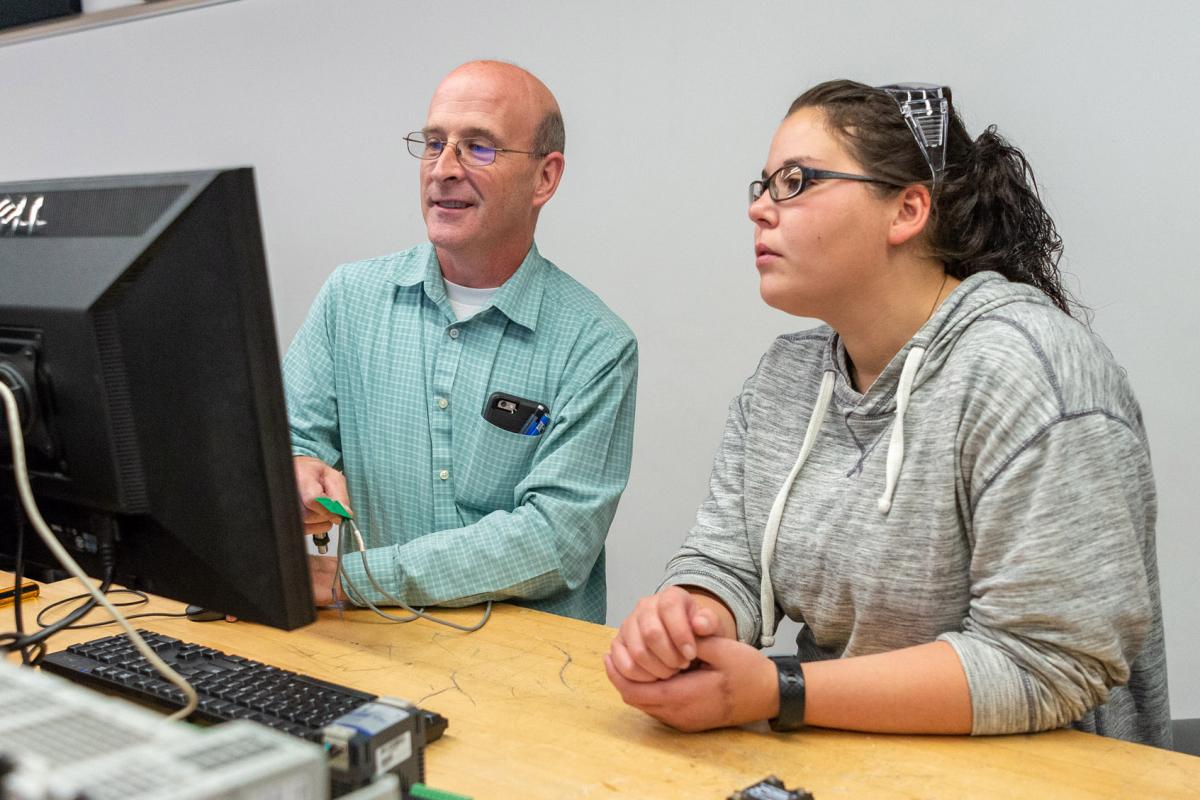  Advisor and student reviewing information together at a computer.