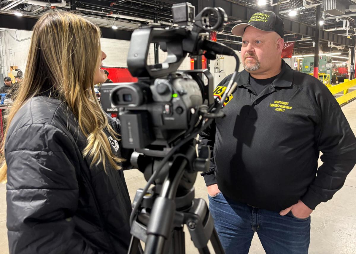 A man talks into a microphone held by a television reporter. They are inside Penn College's welding lab.