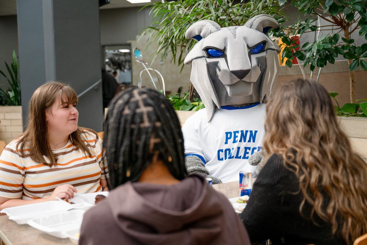 The Wildcat sits with three students in a sunlight lobby.
