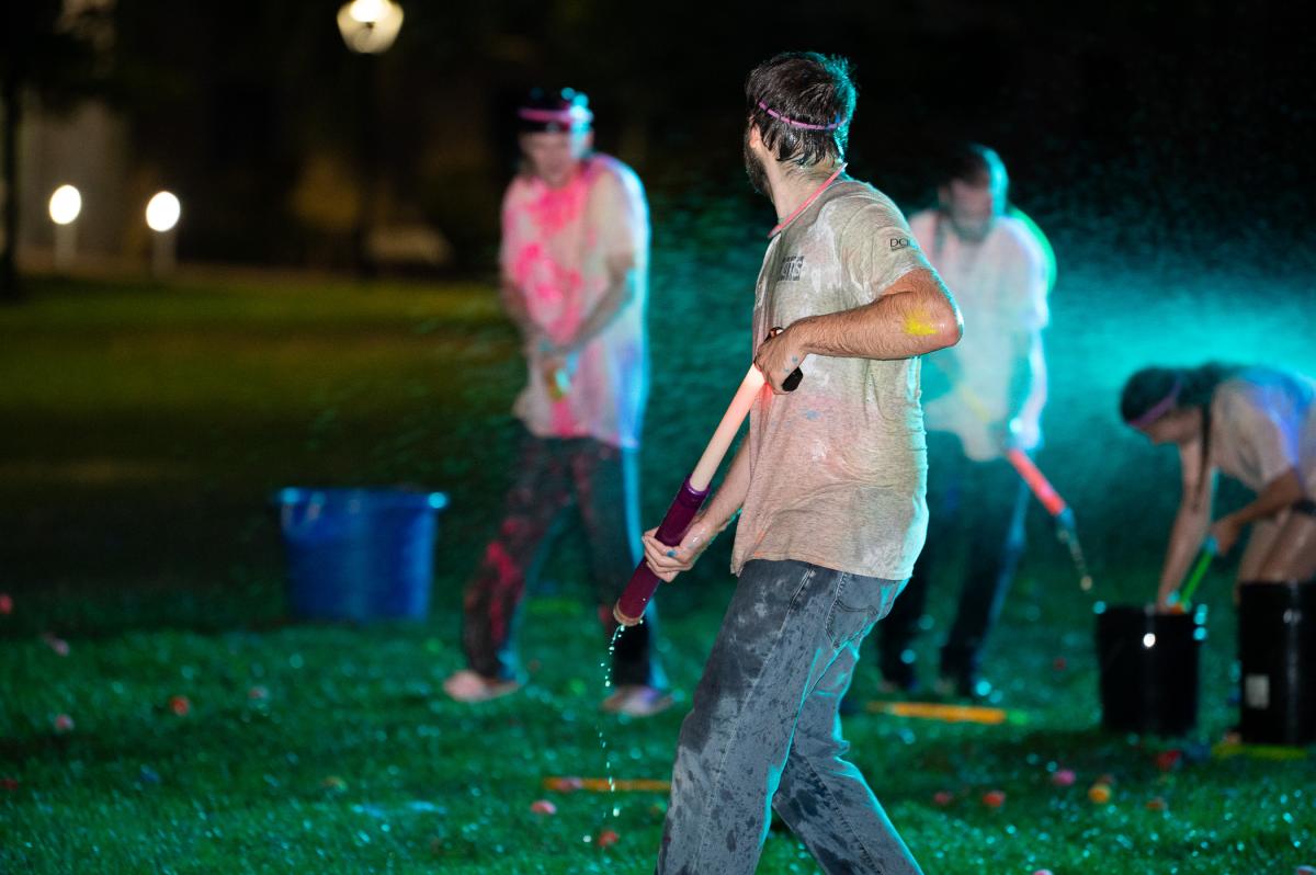 Students "battle" with watercolor guns at night on a lawn