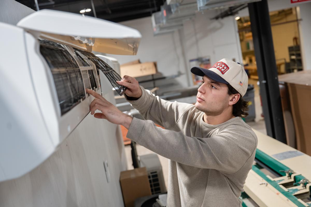 Person adjusting a large machine in an indoor workshop