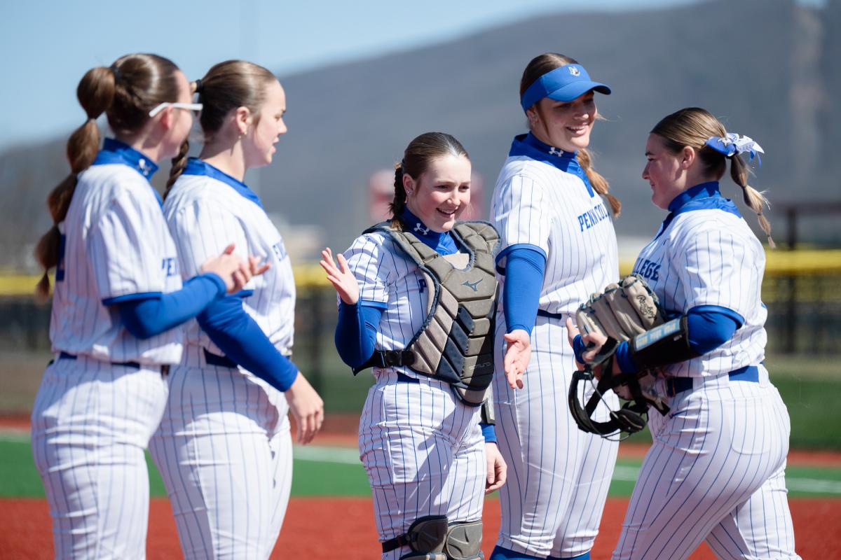 Playes standing on the first-base line high-five a player walking toward them.