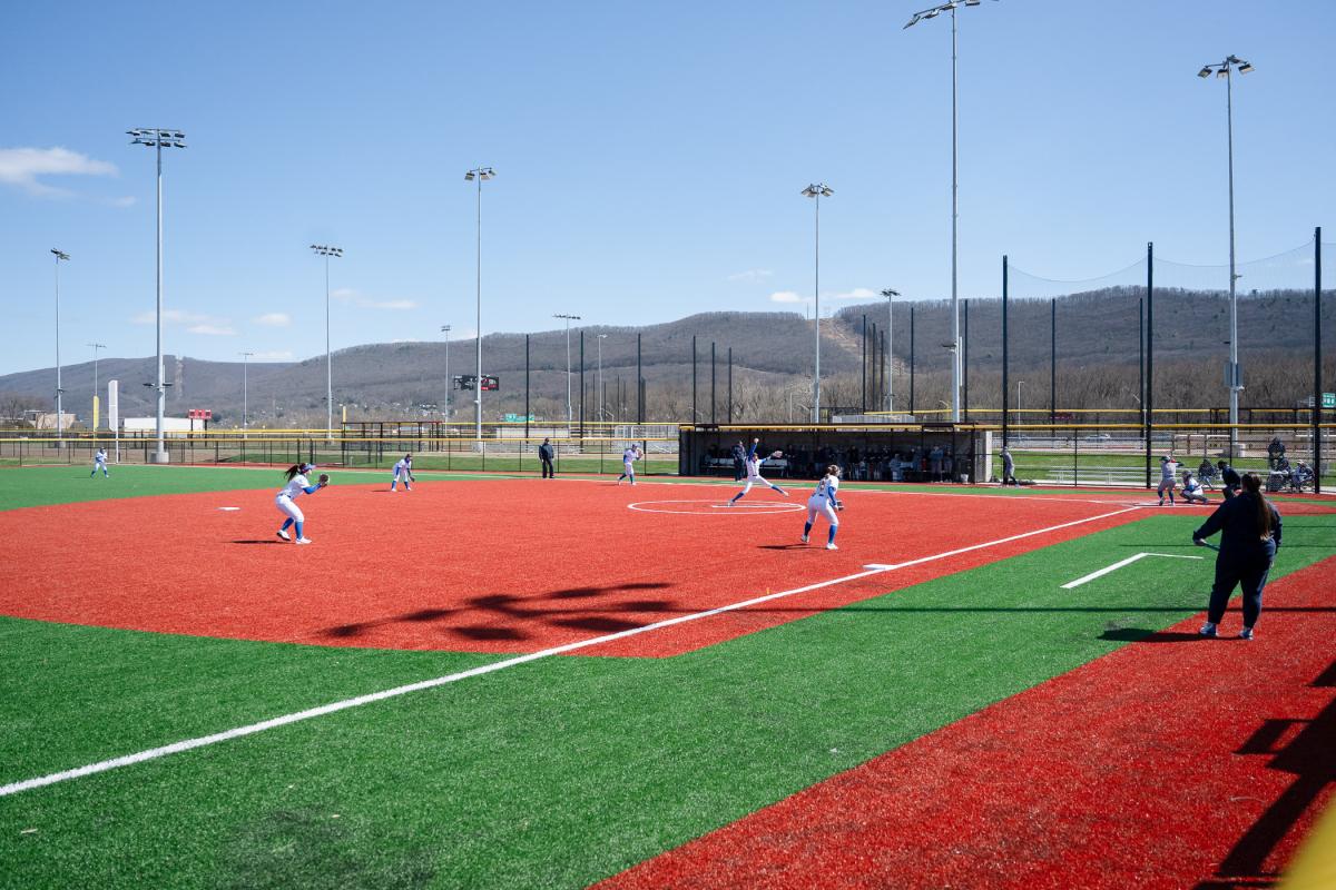 Wide view of a softball game, with Bald Eagle Mountain ridge in the background.