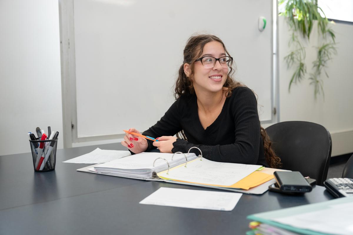 Tutor looking off camera, sitting at a desk with a notebook.