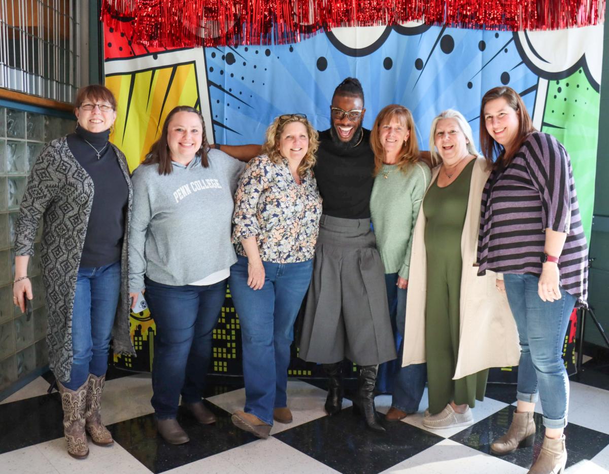 A group of people stands in front of a colorful photo backdrop.