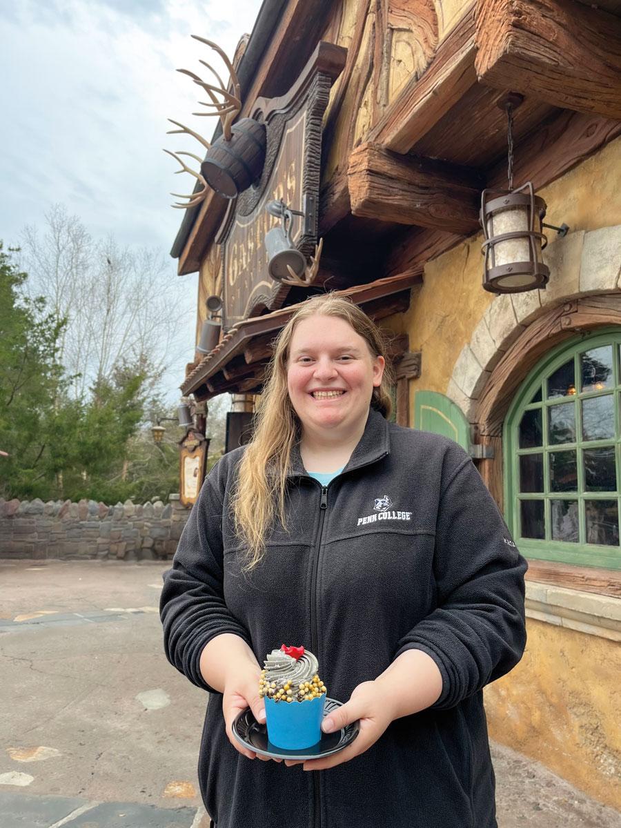 Baking & pastry arts graduate Corrina Blose poses in front of the Be Our Guest Restaurant  in Walt Disney World’s Magic Kingdom.