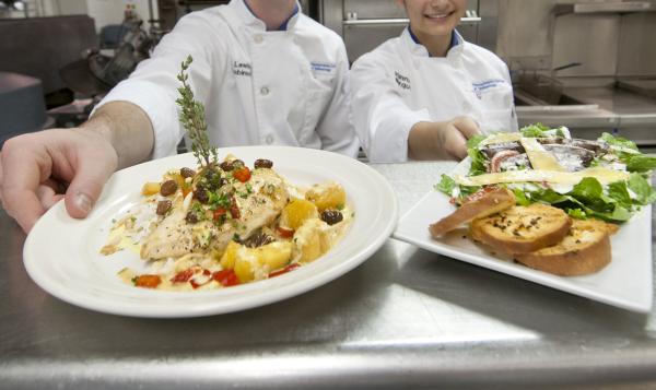 A Penn College culinary student works in a professional kitchen lab, developing hands‑on cooking and food preparation skills.