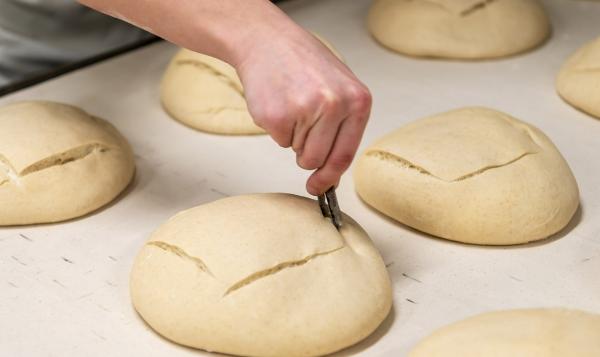 Hand scoring bread dough before baking