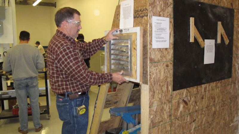 Clean Energy Center instructor Jack Wilson examines a weatherization tactics project.