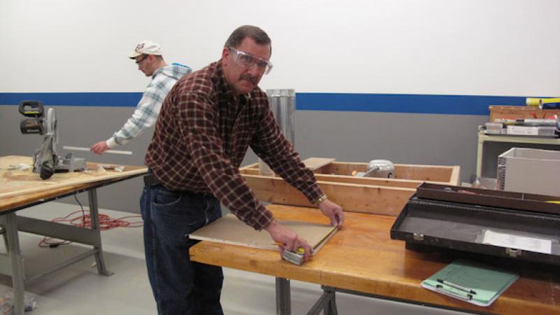 Instructor Jack Wilson takes a measurement for a drywall patch.
