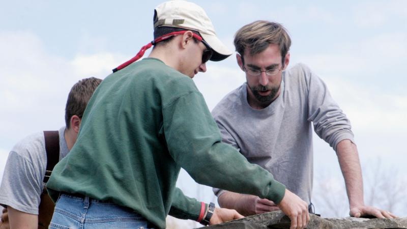 2006: Student Andrew R. Moyer, foreground, positions a stone atop “A Tribute to Knowledge,” a looping dry stone wall at the Earth Science Center entrance, constructed by James A. Asbury, ’02, right, with students.