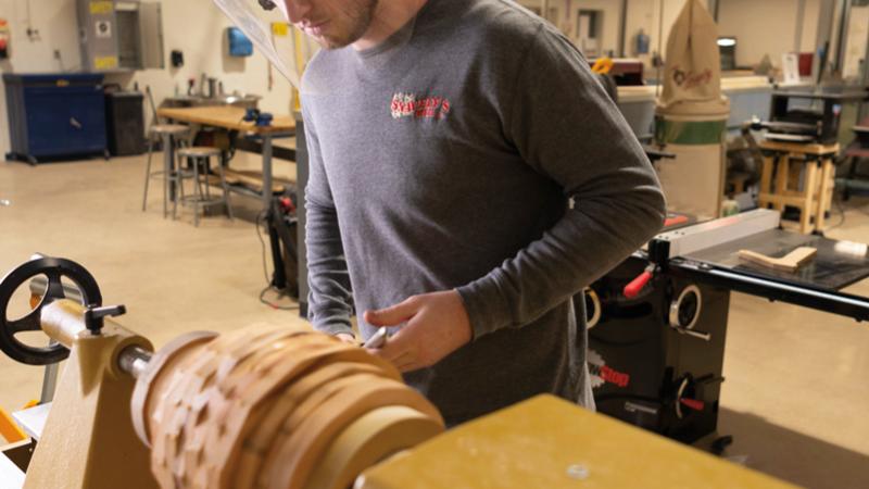 Mason Peters, applied management and heating, ventilation & air conditioning technology, shapes a piece from cherry and black walnut that was harvested at the college's Schneebeli Earth Science Center.