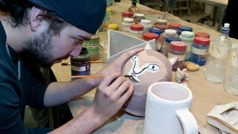 Ceramics student applying glaze to an animal effigy container.
