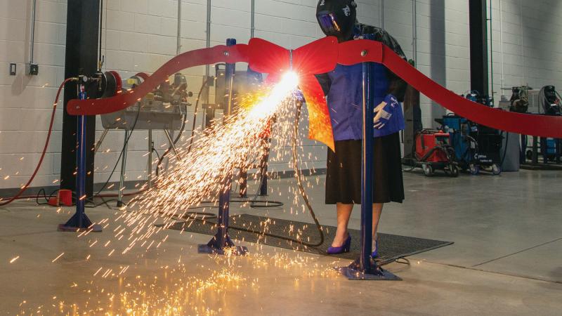 The president deftly wields a plasma cutter to sever a metal ribbon during a dedication ceremony for the expanded Lycoming Engines Metal Trades Center in 2020.