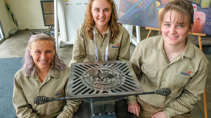 Beaver, right, as part of the all-female welding fabrication team from Penn College at the 2018 SkillsUSA National Championships, shows the rocket stove they built. Beaver was joined in the effort by Joelle E. Perelli, left, and Natalie J. Rhoades.