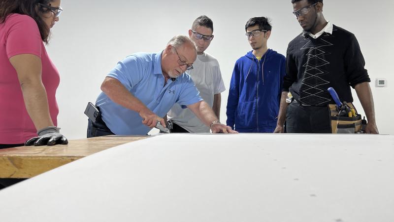 teacher demonstrating drywall cutting to students