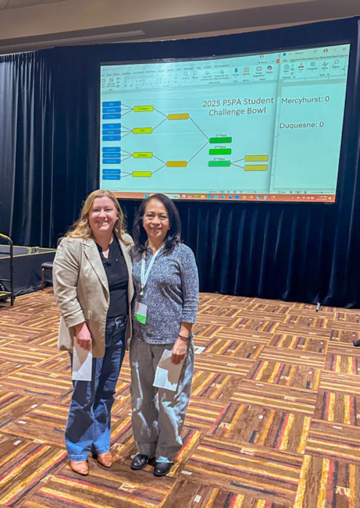 Two women stand together in a conference room.