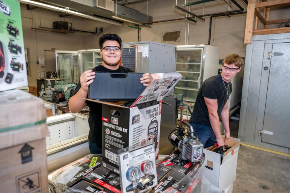 Students smile as they remove tools and equipment from boxes in Penn College's refrigeration labs.