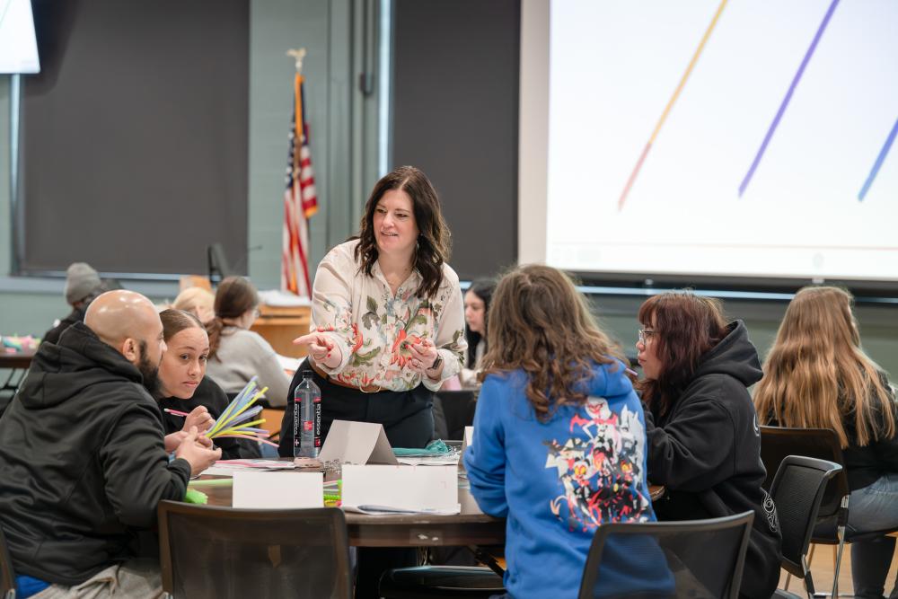 A woman interacts with students who are seated at a round table Penn's Inn at Penn College.
