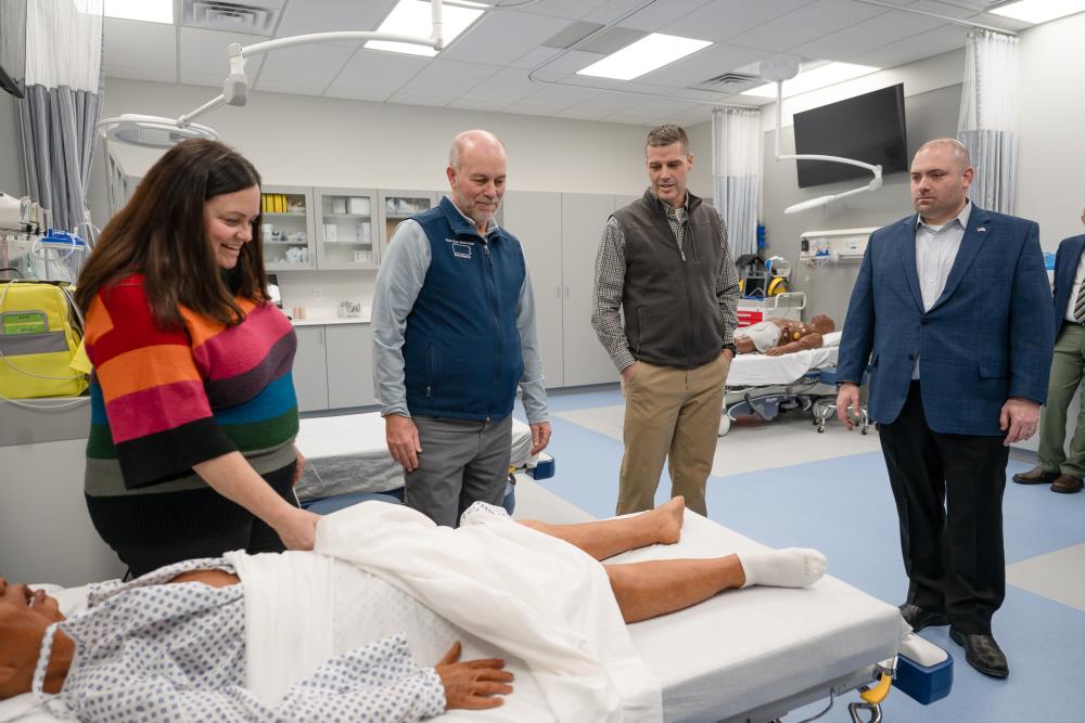 People gather around a medical manikin lying in a hospital bed in Penn College's Physician Assistant Center.