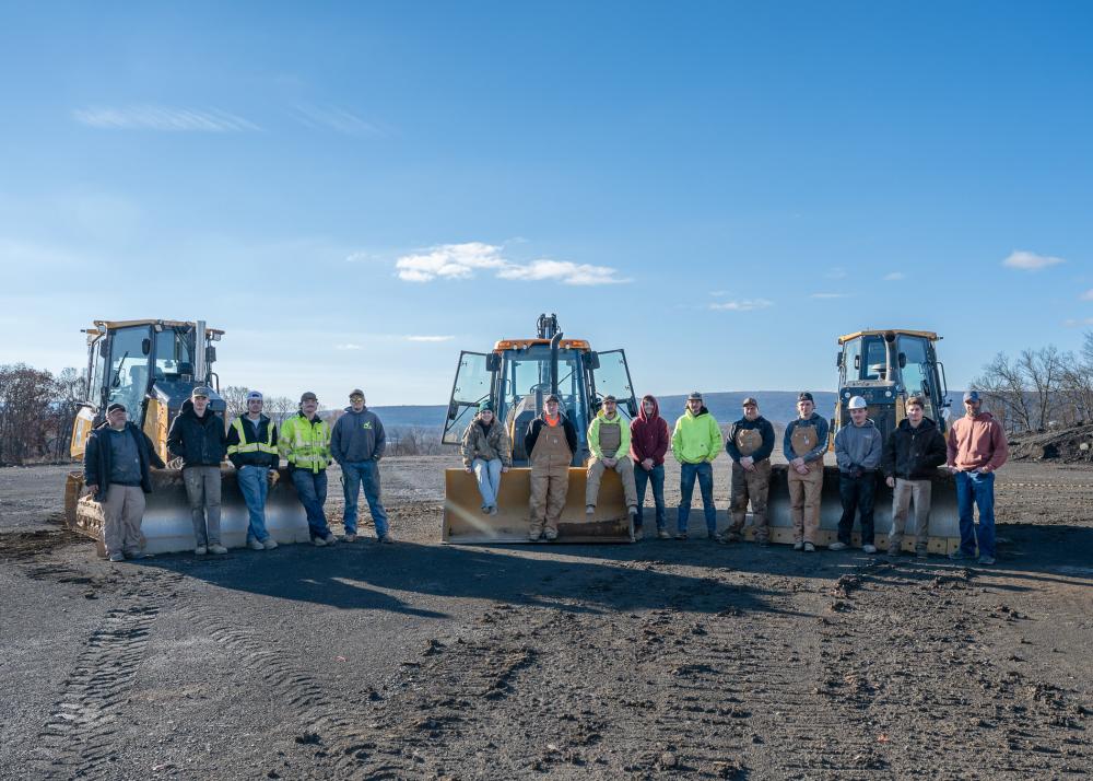 Penn College students gather around heavy equipment at the college's traning site.