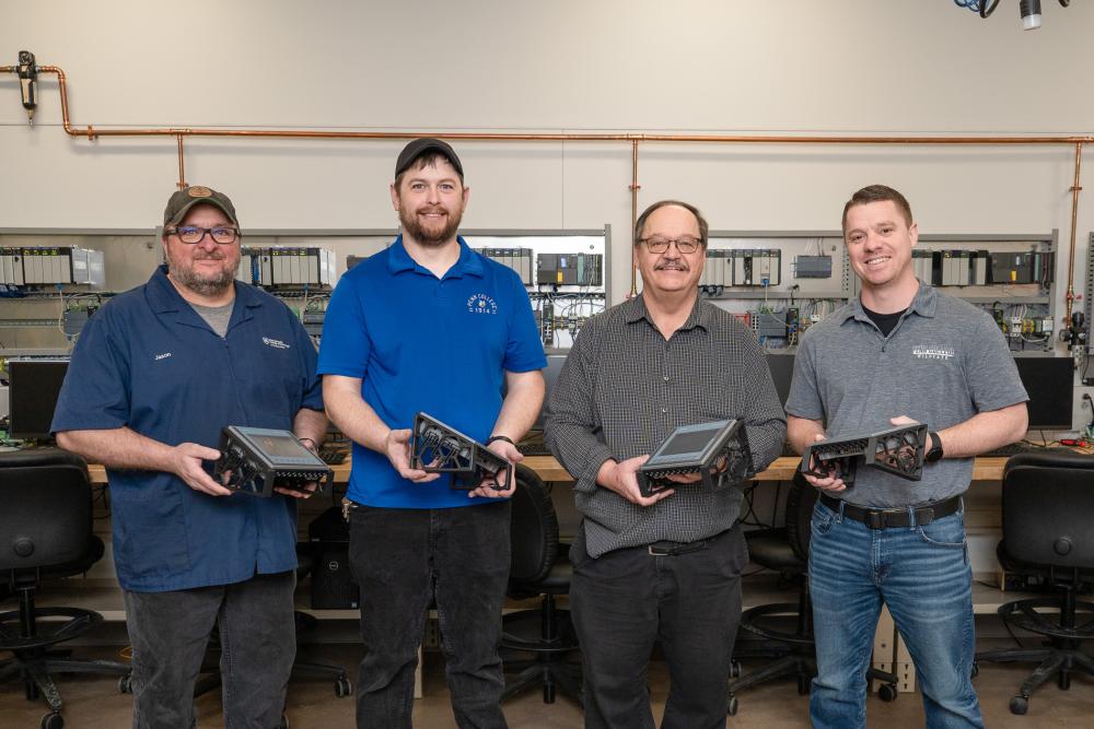 Four Penn College employees hold frames for human-machine interfaces.