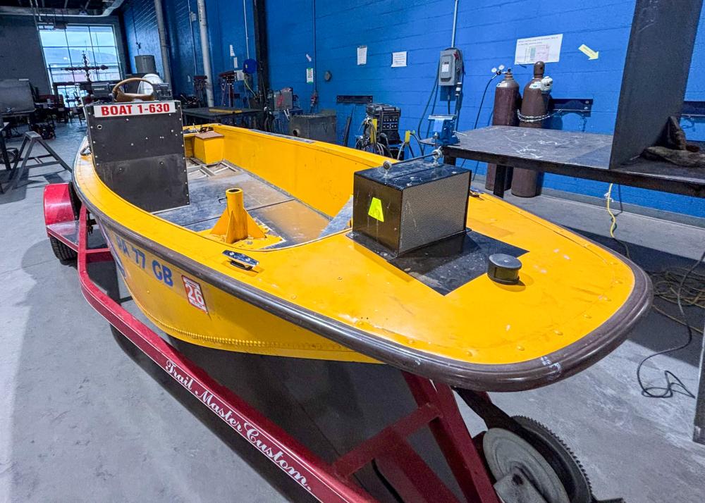 The Montgomera Emergency Managemen Agency's birght yellow rescue boat sits on a trailer in Penn College's welding lab.