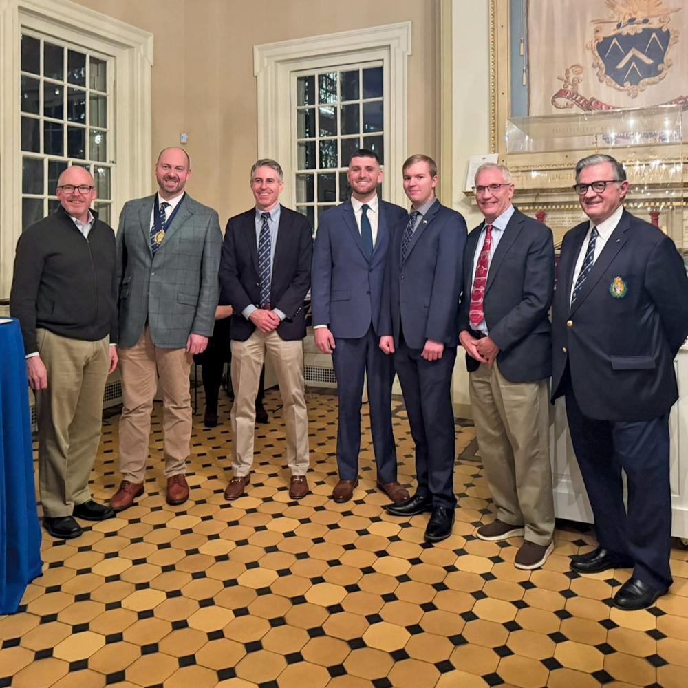 A group of men in business suits stand in the interior of a historic building.
