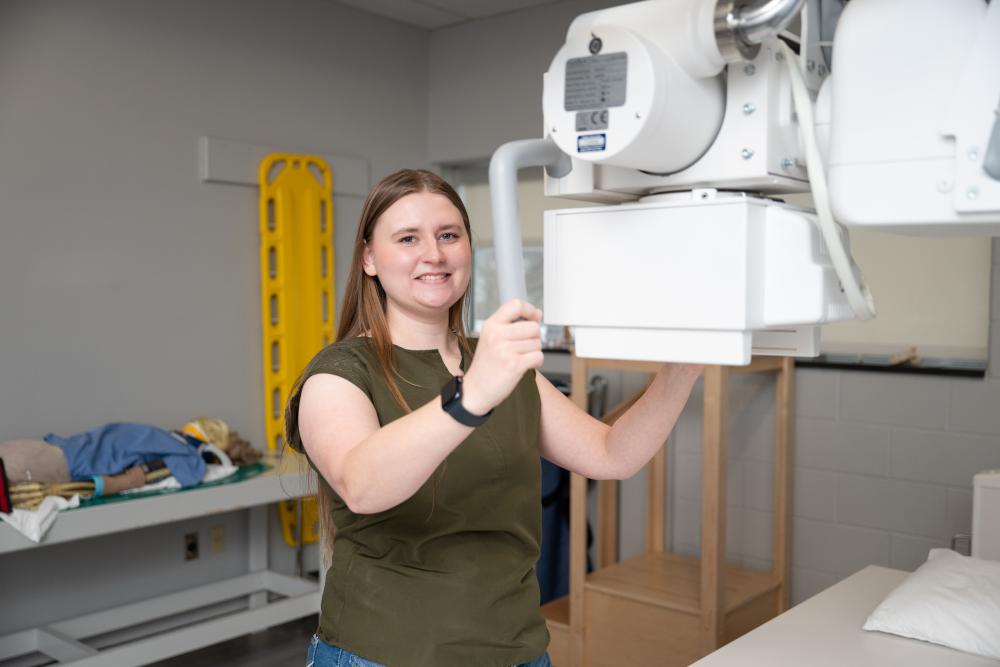 Kelsey Bennett with hands on X-ray equipment in Penn College lab.