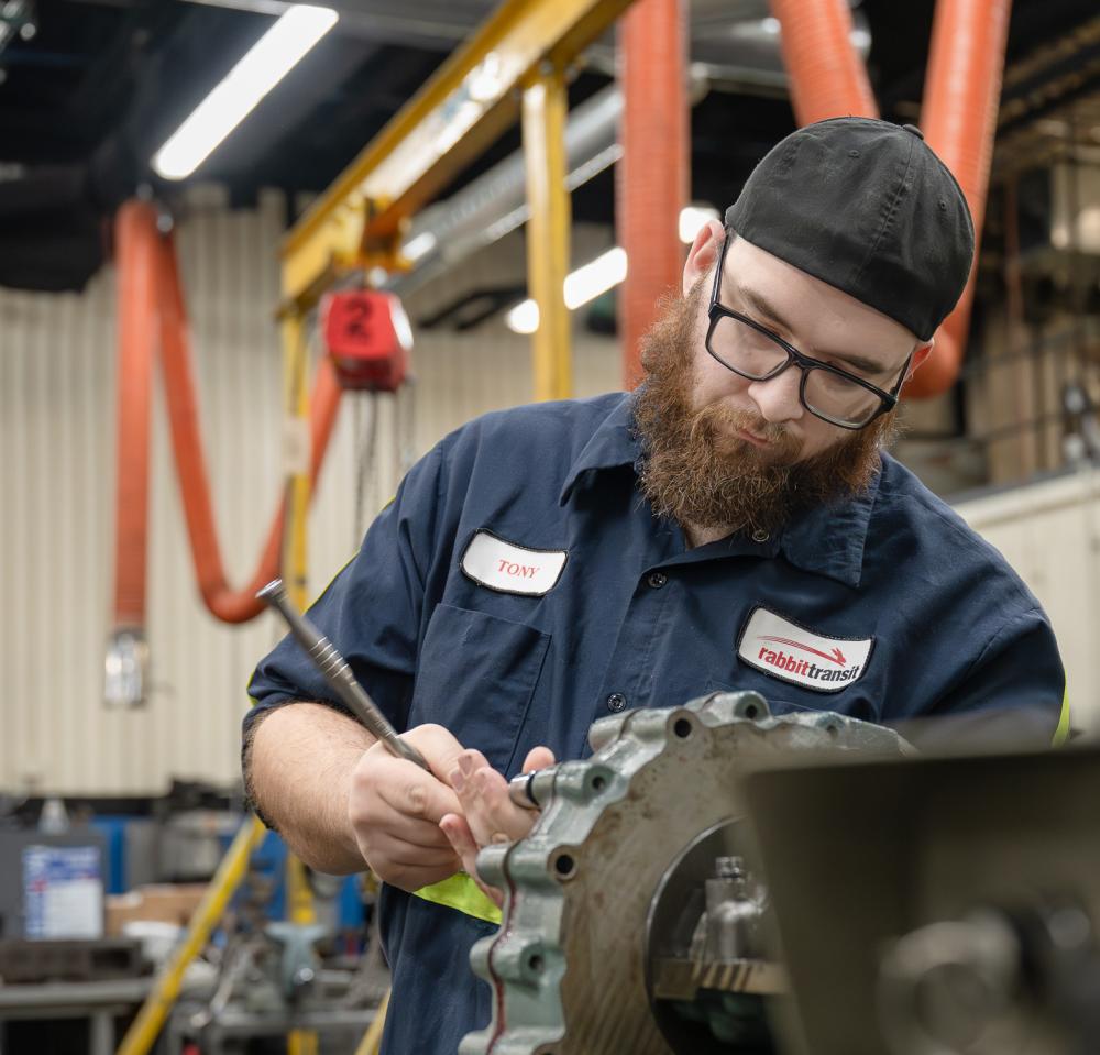 A bus maintenance technician apprentice works on a transmission