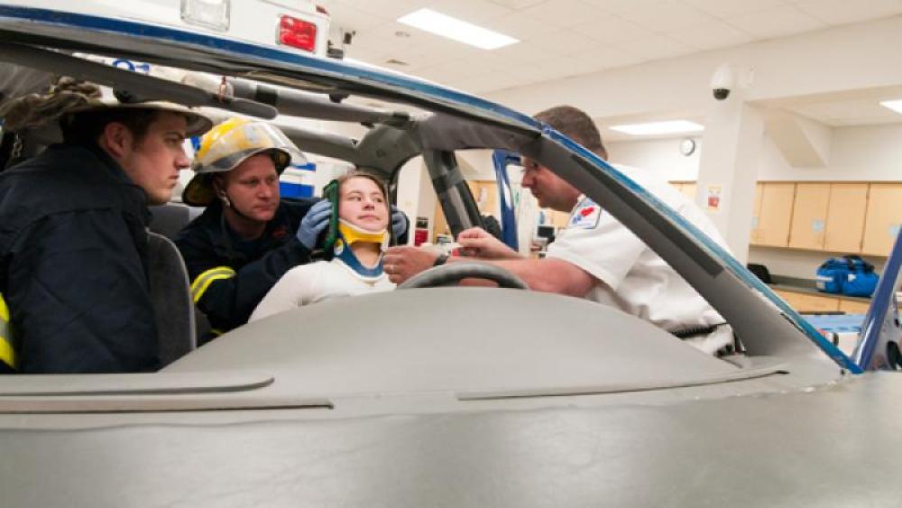 Students practice immobilizing a patients neck in a simulation vehicle