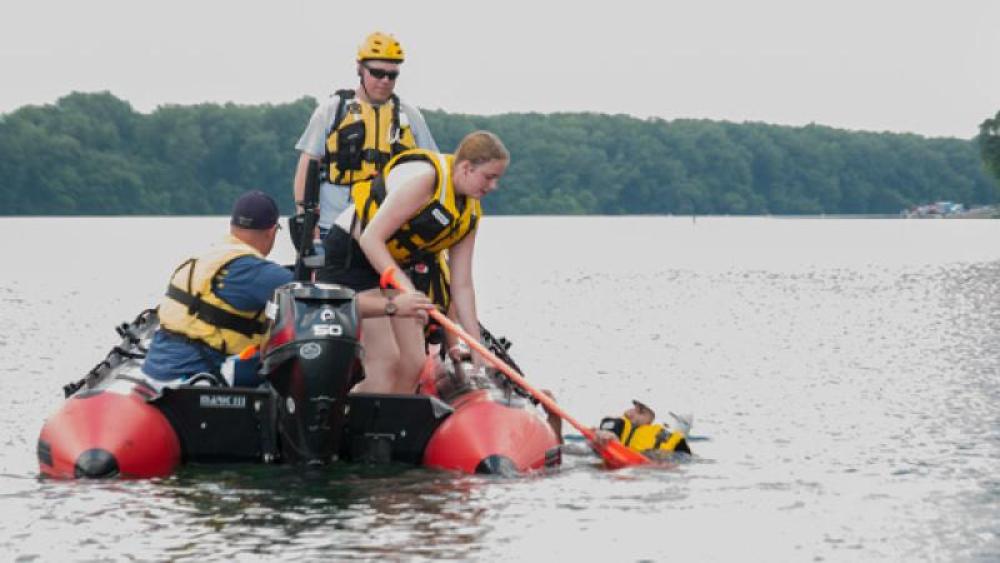 Emergency personnel practice a rescue on a lake from a motorized raft.