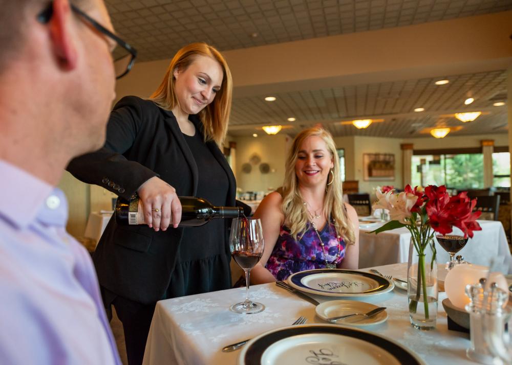 A le Jeune Chef host pours a glass of wine for a guest