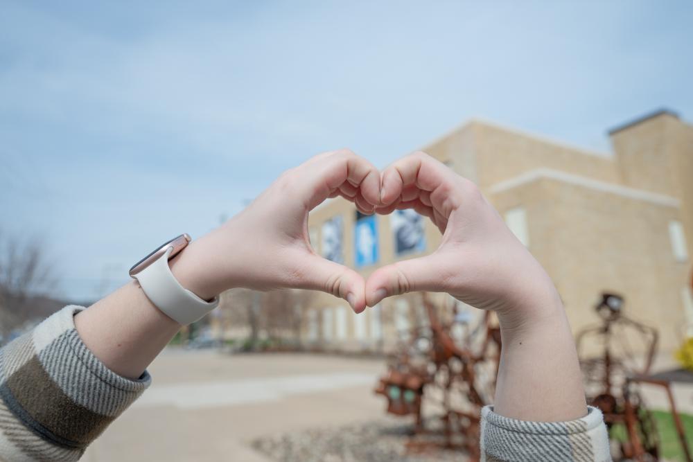 Student holding hands up in the shape of a heart