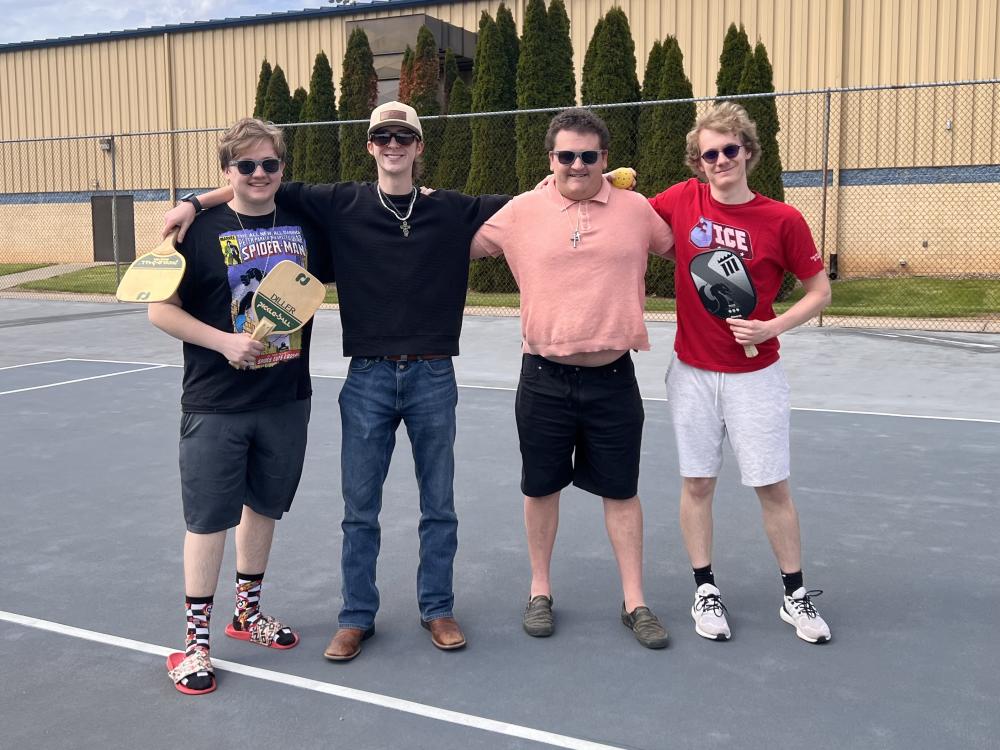 Students holding pickleball paddles on a court